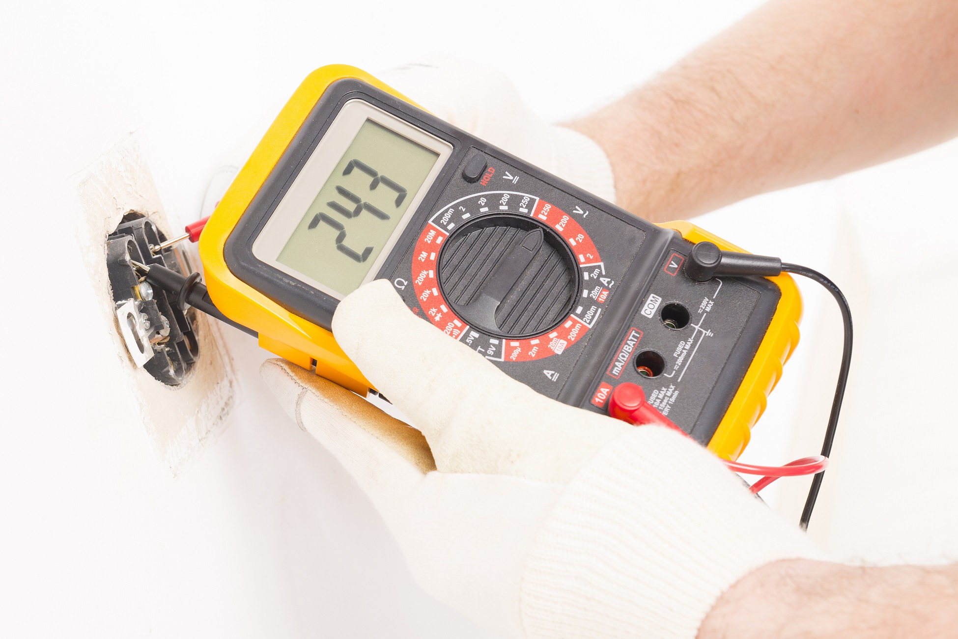 Electrician checking socket voltage with digital multimeter