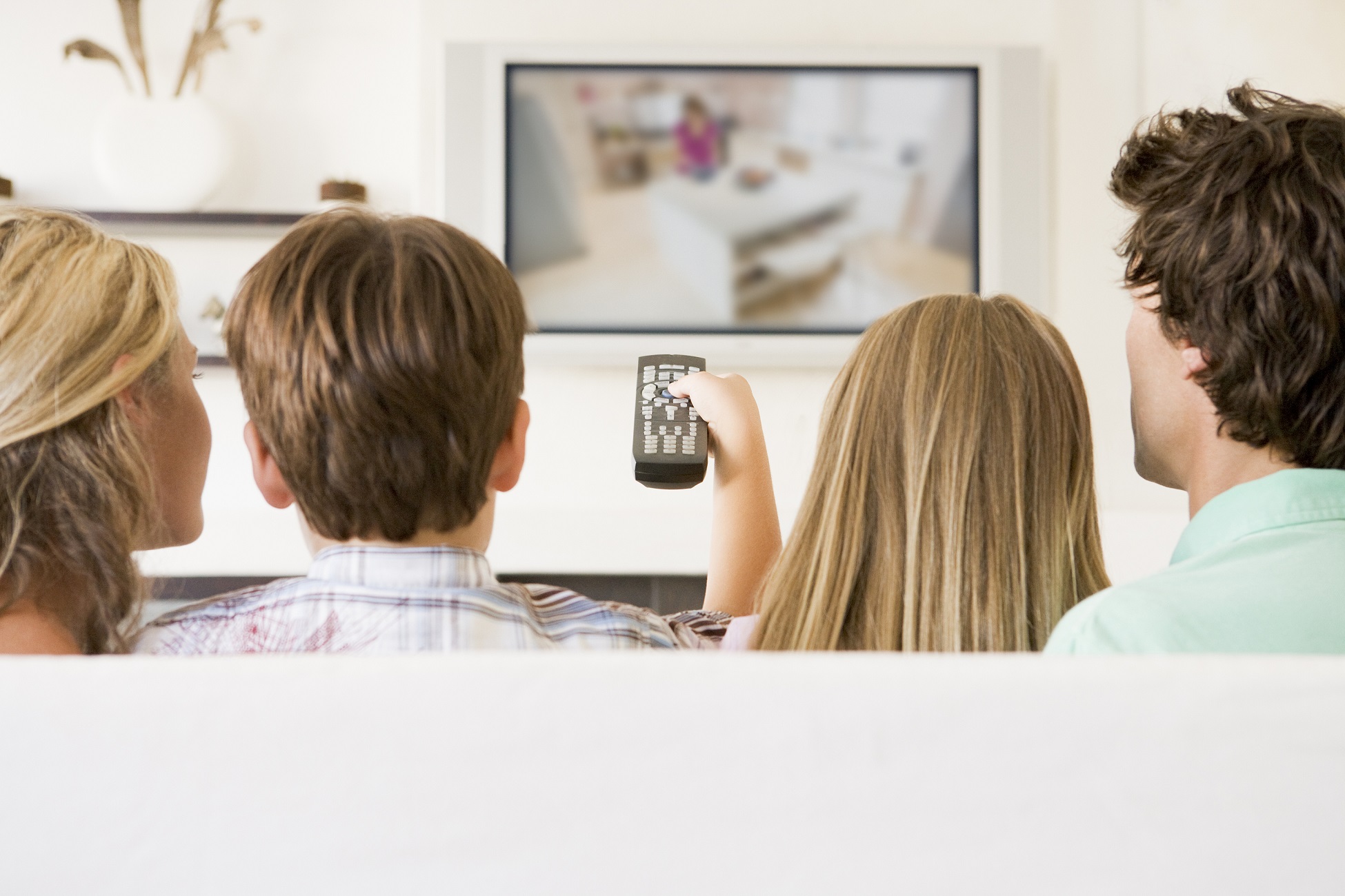 Families In Living Room With Remote Control And Flat Screen Tele